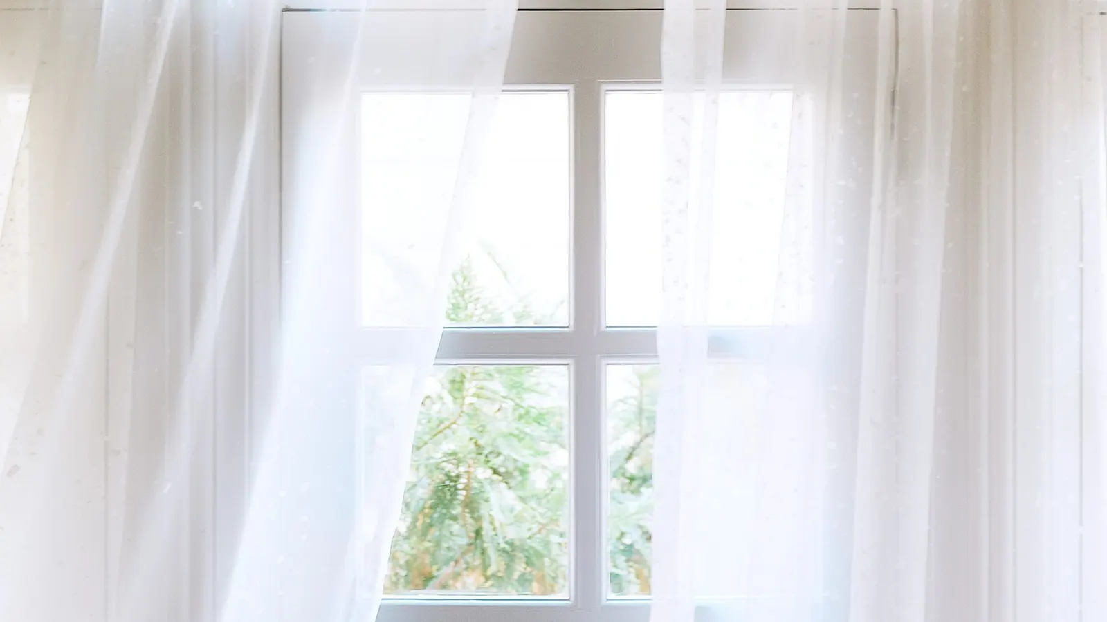 Sheer white curtain folds framing a sunlit window