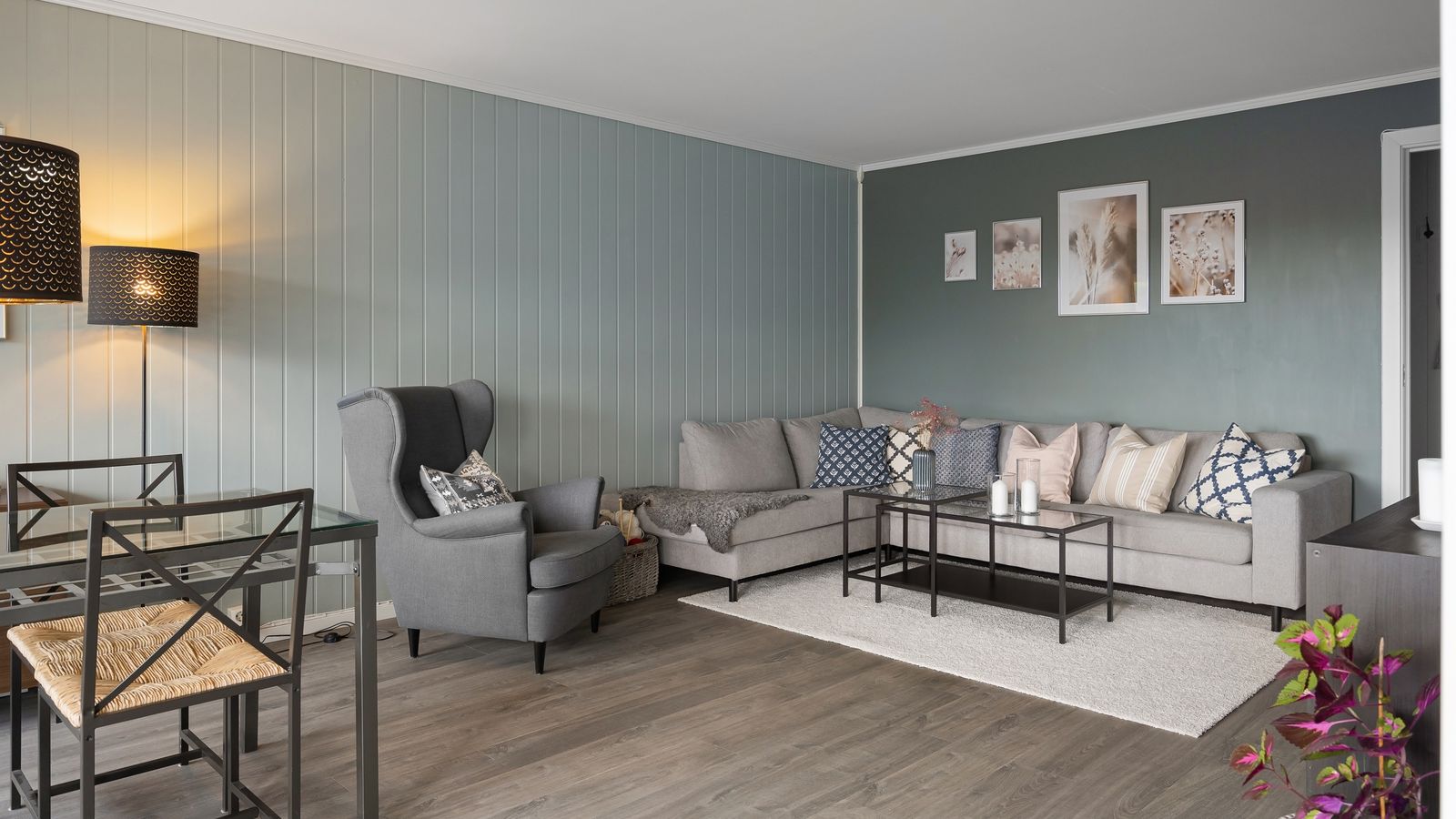Living room with muted green and grey painted walls, a grey corner sofa, and an armchair.