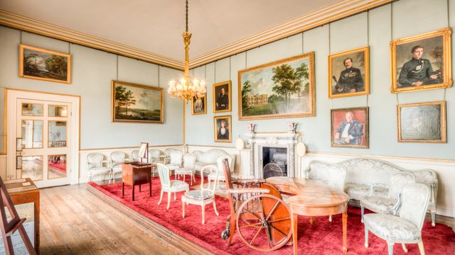 Period room featuring pale sage green walls, classic mouldings, a fireplace, and antique furnishings.